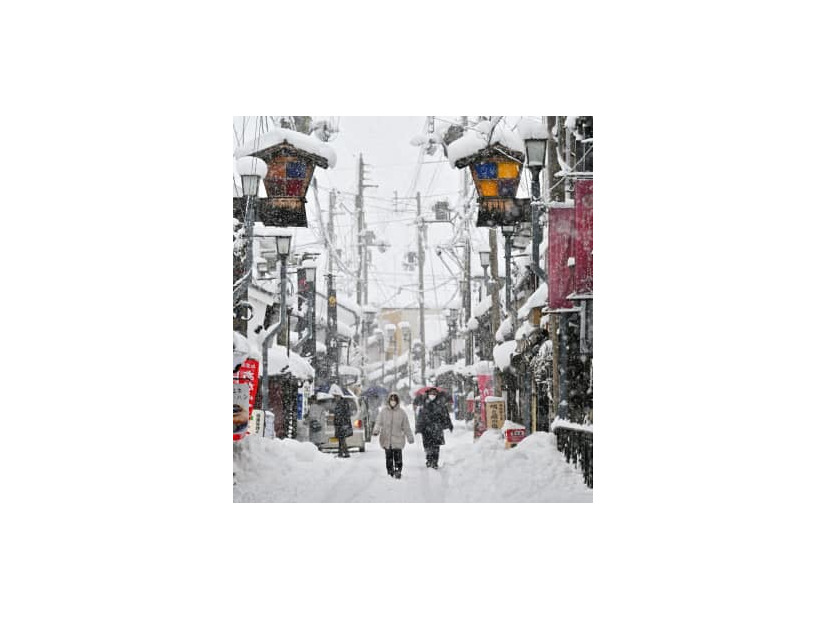 雪が降り続く中、滋賀県長浜市内を歩く人たち＝5日午後