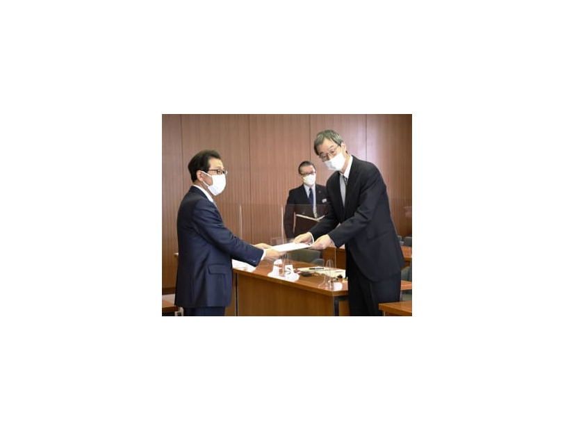 札幌市の秋元克広市長（左）に児童虐待防止の取り組みへの評価報告書を手渡した松本伊智朗・北海道大大学院教授＝17日午後、同市役所