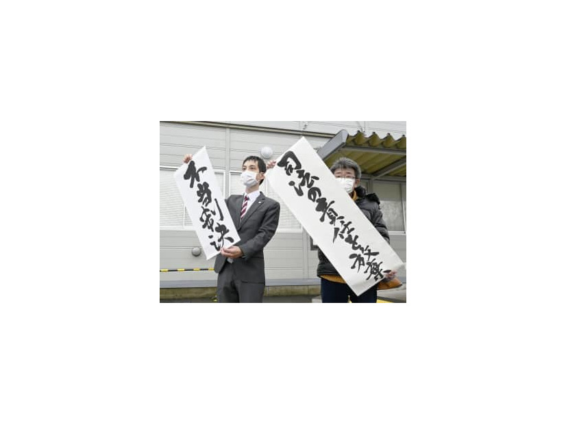 生活保護費の基準額引き下げを巡る訴訟の判決を受け、「不当判決」などと書かれた紙を掲げる弁護士ら＝7日午後、秋田地裁前