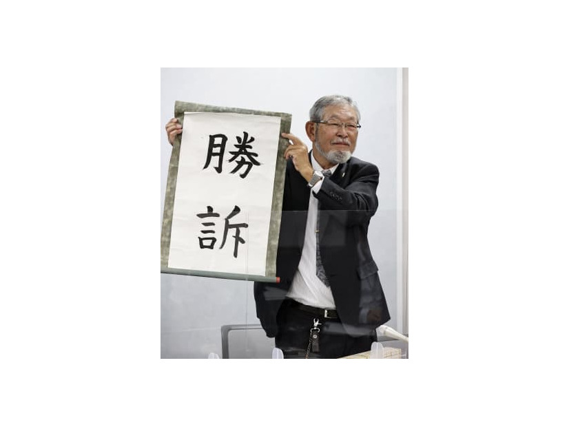 「勝訴」と書かれた垂れ幕を掲げる大阪府泉佐野市側代理人の阿部泰隆弁護士＝10日午後、大阪市