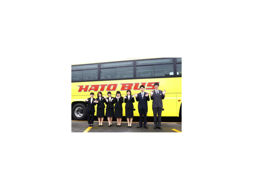 入社式を終え、はとバスを背にポーズをとる新入社員＝1日午前、東京都大田区