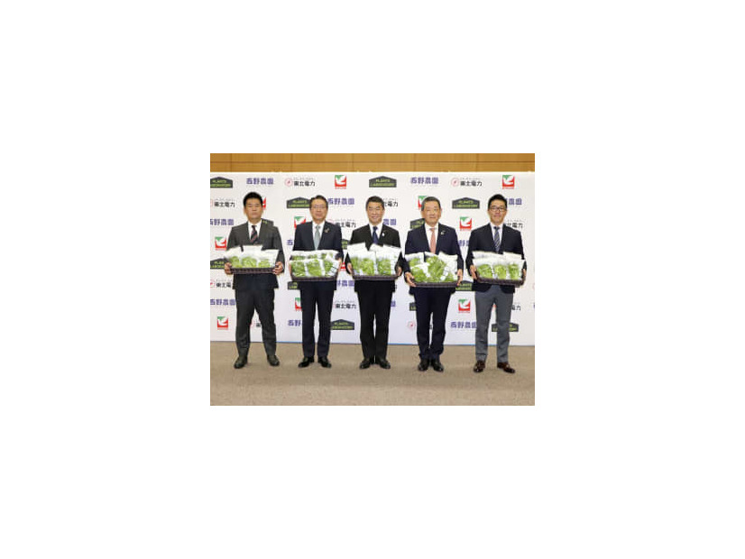 出荷するレタスを手に記念撮影する西野農園の西野拓社長（右端）ら＝6日午前、仙台市
