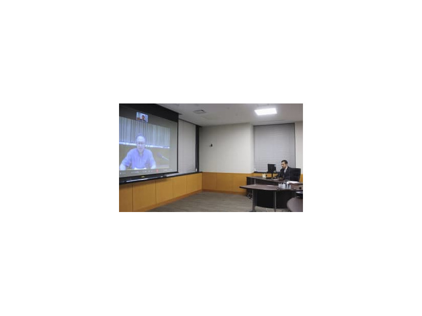 オンラインで沖縄県の玉城デニー知事（画面）と意見交換する山際経済再生相＝14日午後、内閣府
