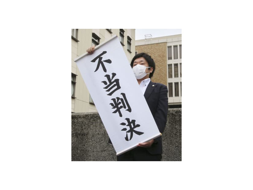 判決後、「不当判決」と書かれた幕を掲げる弁護士＝20日午前、さいたま地裁前