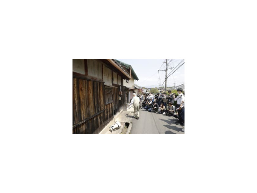 滋賀県日野町の強盗殺人事件で、殺害現場とされる酒店だった建物の前で説明を受ける報道関係者ら＝23日午後