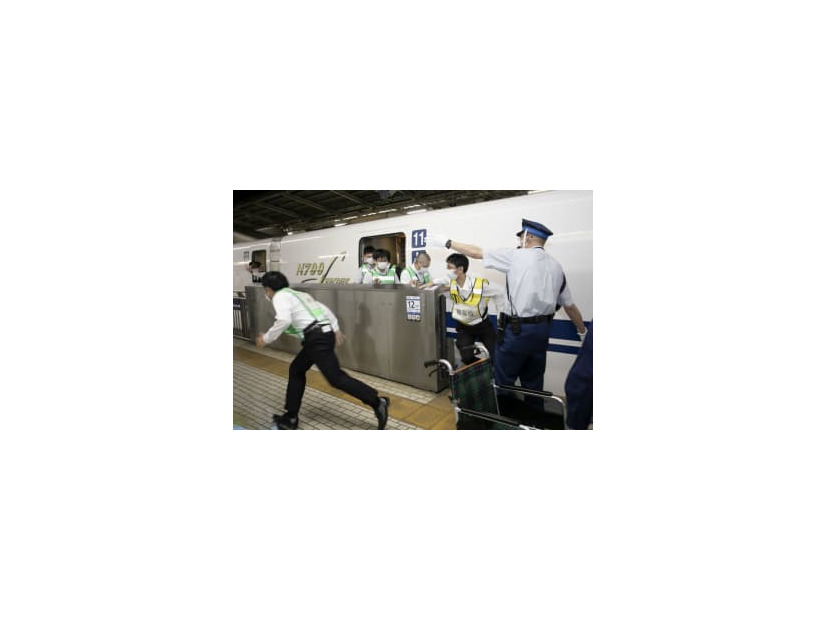 新幹線が本来の位置からずれて停車しながらも、ホームドアを開けて乗客役を避難誘導する駅員＝14日未明、JR新横浜駅