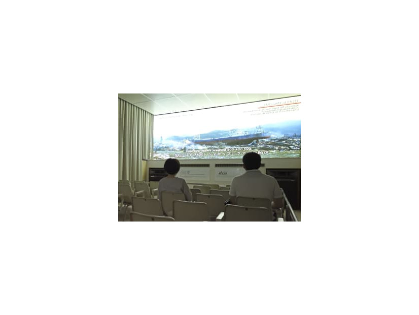 閉館の日を迎えた津波体験館で映像を見る来館者＝26日午後、宮城県気仙沼市