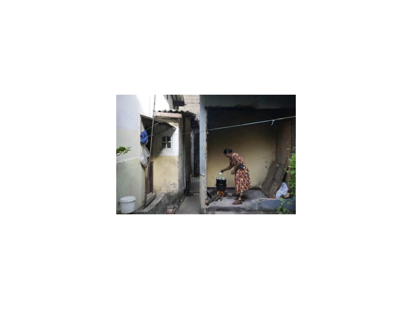 まきを燃やして料理する女性＝6月23日、スリランカ・コロンボ（AP＝共同）