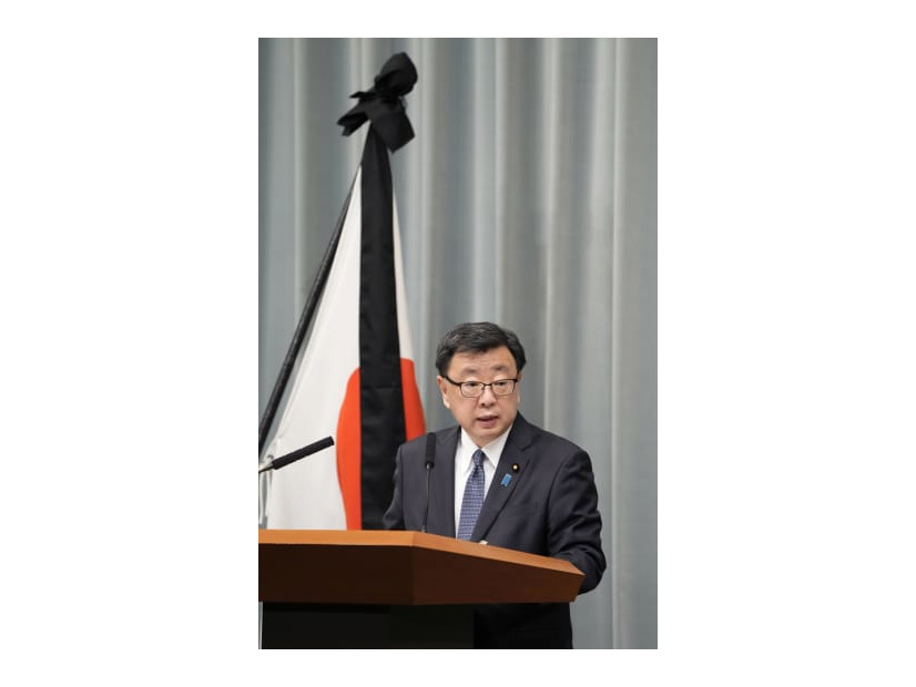 弔旗の前で記者会見する松野官房長官＝11日午前、首相官邸