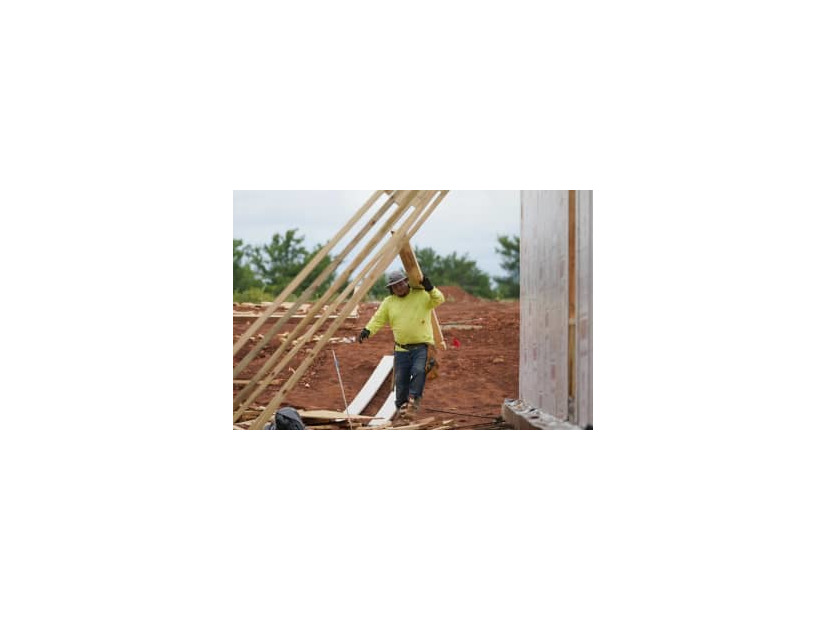 住宅建設現場で板を運ぶ作業員＝2021年6月、米オクラホマ州（AP＝共同）
