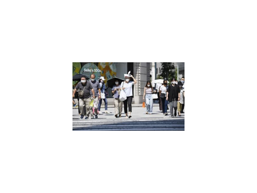 強い日差しの中、マスク姿で横断歩道を渡る人たち＝9日午後、東京都中央区
