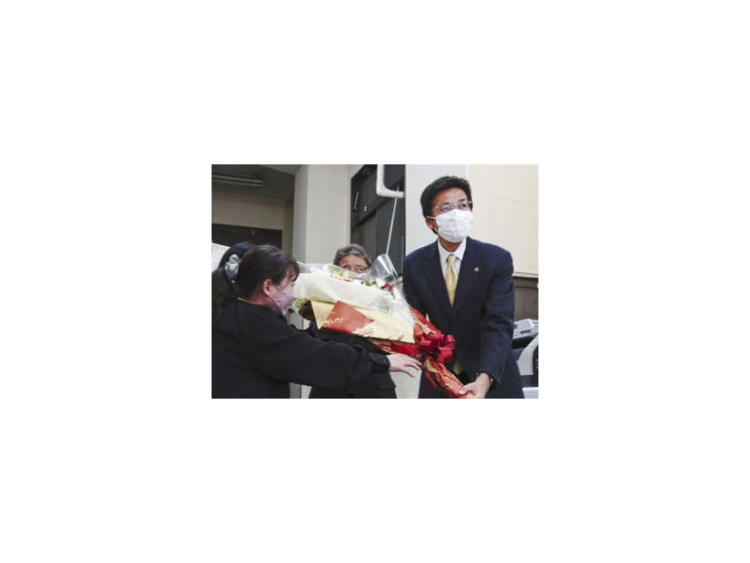 当選が決まり、事務所で花束を受け取る斉藤栄氏（右）＝11日夜、静岡県熱海市