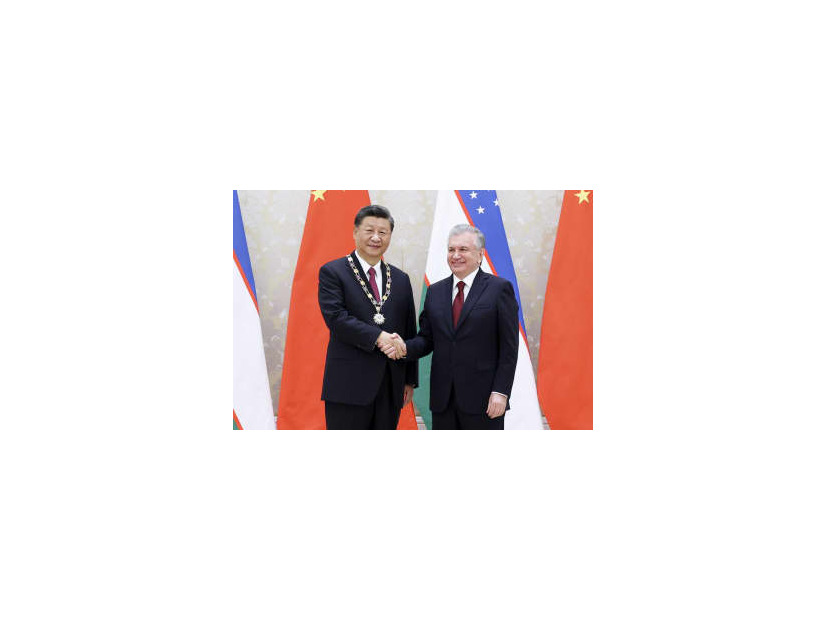 15日、ウズベキスタン・サマルカンドでミルジヨエフ大統領（右）から勲章を授与され握手を交わす中国の習近平国家主席（新華社＝共同）