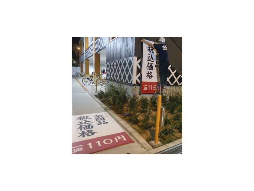 価格が表示された垂れ幕を交換するくら寿司朝潮橋店の従業員＝9月30日夜、大阪市港区