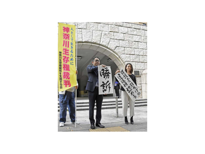 生活保護費減額処分の取り消しなどを求めた訴訟の判決後、「勝訴」と書かれた紙を掲げる弁護士ら＝19日午前、横浜地裁前