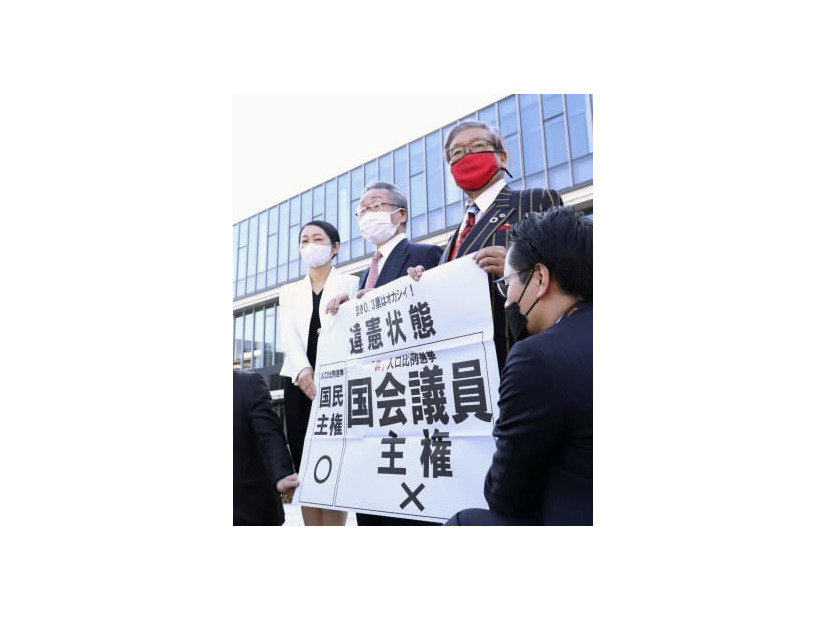 名古屋高裁金沢支部前で「違憲状態」と書かれた紙を手にする原告側の弁護士ら＝10日午後