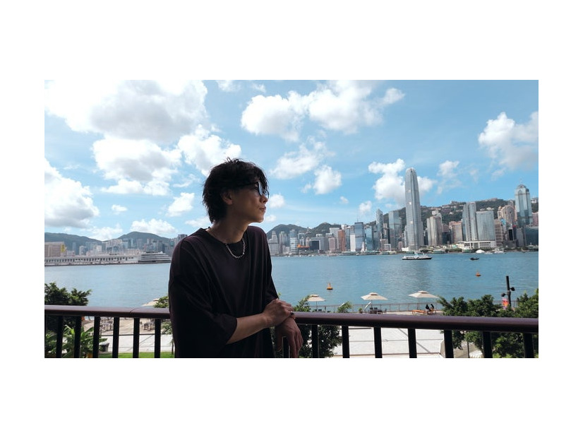 ビクトリア・ハーバー越しに香港を象徴する高層ビル群を望む佐藤健／提供画像