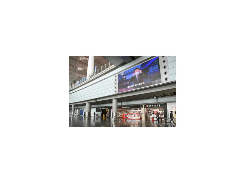 閑散とする北京首都国際空港の到着ロビー。大型モニターにはマスク着用を呼び掛ける映像が流れていた＝12日（共同）