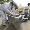 セメントのようなもので埋められた鉢の修復作業。奥は原爆供養塔＝20日午前、広島市の平和記念公園