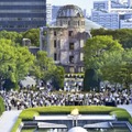 昨年8月6日、広島市の平和記念公園で黙とうする人たち。後方は原爆ドーム
