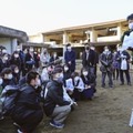 被災した宮城県石巻市立大川小の校舎前で、高校生らに講話する佐藤敏郎さん（右端）＝8日午後