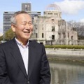 原爆ドーム（後方右）のそばで、インタビューに答える秋葉忠利氏＝2020年2月、広島市