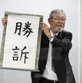 「勝訴」と書かれた垂れ幕を掲げる大阪府泉佐野市側代理人の阿部泰隆弁護士＝10日午後、大阪市