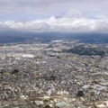 富士山（奥）と静岡県富士宮市の市街地。「富士山火山防災対策協議会」は噴火に備えた避難計画を部分改定する中間報告書を公表した＝30日午後（共同通信社ヘリから）