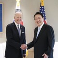 21日、ソウルで初会談し、握手するバイデン米大統領（左）と韓国の尹錫悦大統領（大統領府提供・共同）