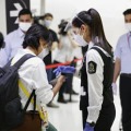 成田空港に到着し、空港職員（手前右）に携帯電話の専用アプリ画面を見せる人＝1日
