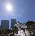 厳しい暑さの中、マスク姿で歩く人たち＝27日午前、JR東京駅前