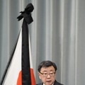 弔旗の前で記者会見する松野官房長官＝11日午前、首相官邸