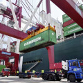 中国山東省青島市の港でつり上げられるコンテナ＝6月（新華社＝共同）