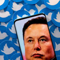 スマートフォンに映し出されたテスラCEOのイーロン・マスク氏。周りにはツイッターのロゴ＝4月（ロイター＝共同）