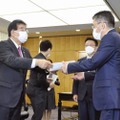 KDDIの高橋誠社長（手前右）に行政指導の文書を渡す金子総務相＝3日午後、総務省