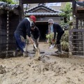 ボランティアと泥をかき出す男性（左）＝8日、福井県南越前町