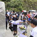 学童疎開船「対馬丸」をテーマにした学習事業で、慰霊碑に花を供える子どもたち＝20日午前、鹿児島県宇検村