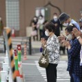 安倍元首相銃撃事件の現場付近で手を合わせる人たち＝27日午後1時21分、奈良市