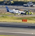 誘導路上でパンクした小型航空機。手前は福岡空港の滑走路＝20日午後4時37分