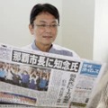 那覇市長選から一夜明け、初当選を報じる新聞を手にする知念覚氏＝24日午前、那覇市