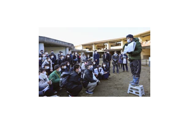 被災した宮城県石巻市立大川小の校舎前で、高校生らに講話する佐藤敏郎さん（右端）＝8日午後