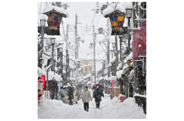 雪が降り続く中、滋賀県長浜市内を歩く人たち＝5日午後