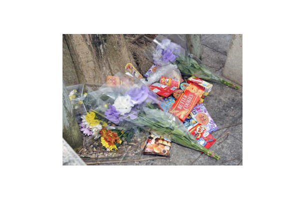 女児がベランダから転落死した市営住宅に手向けられた花束や菓子＝9日午前、沖縄県名護市