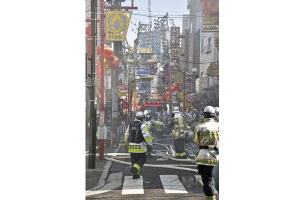 横浜中華街の火災現場付近で、消火活動をする消防隊員ら＝11日午前11時24分、横浜市