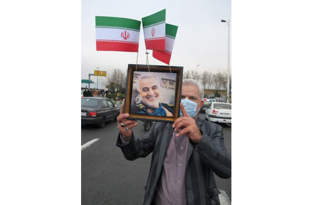 米軍に暗殺されたソレイマニ司令官の写真を掲げる男性＝11日、テヘラン（共同）