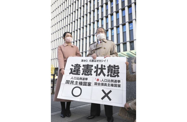 福岡高裁前で「違憲状態」と書かれた紙を掲げる原告側の升永英俊弁護士（右）ら＝21日午後