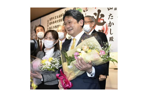 金沢市長選で初当選し、花束を手に笑顔を見せる村山卓氏（手前右）＝13日夜