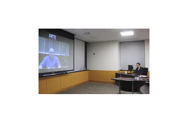 オンラインで沖縄県の玉城デニー知事（画面）と意見交換する山際経済再生相＝14日午後、内閣府