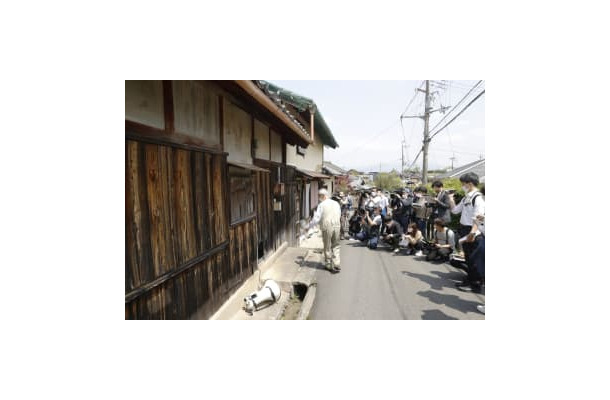 滋賀県日野町の強盗殺人事件で、殺害現場とされる酒店だった建物の前で説明を受ける報道関係者ら＝23日午後
