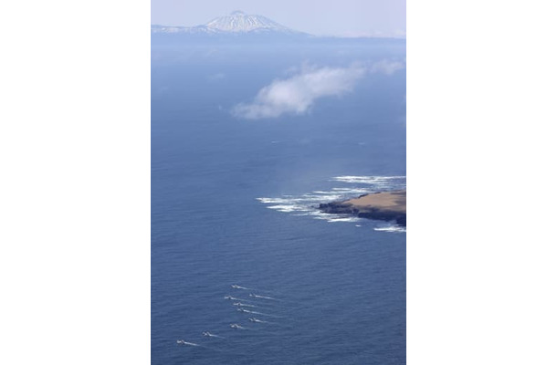 北海道・知床半島沖で捜索する漁船団（左下）。奥は国後島＝30日午前10時24分（共同通信社ヘリから）